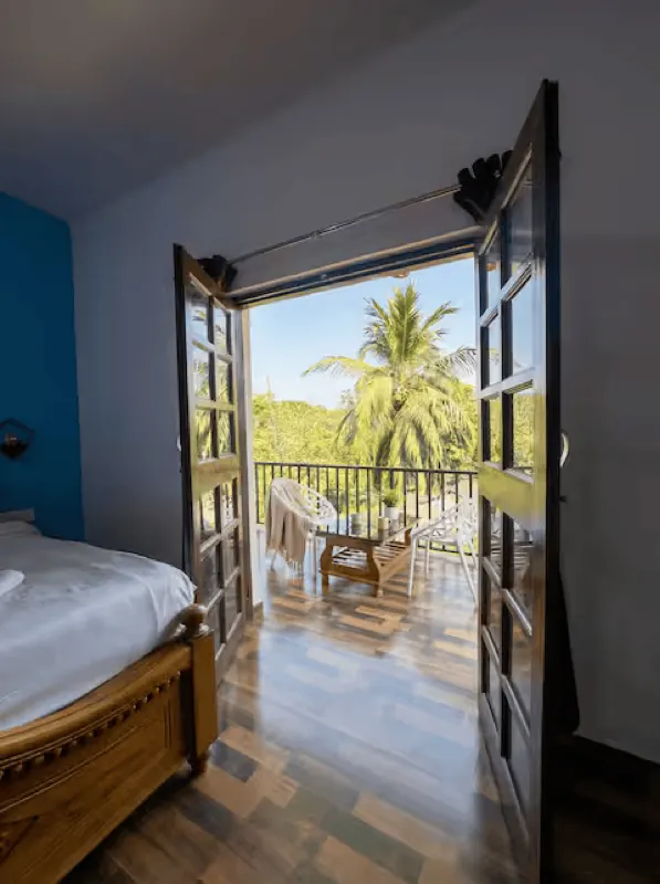 Bedroom door opening onto a balcony with palm views
