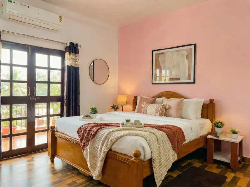 King bedroom with a pink wall and French windows
